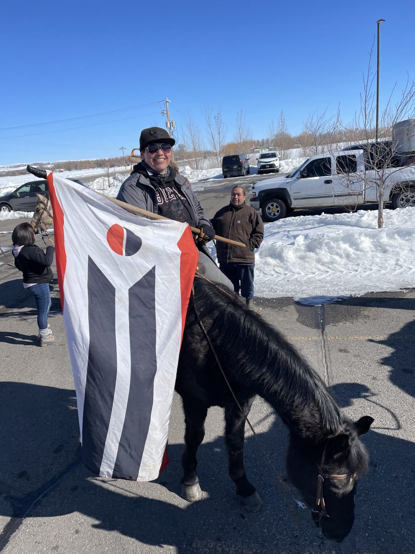 MiRae on a horse holding the Arapaho flag