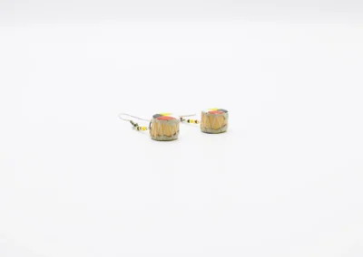 Colorful drum-shaped earrings with decorative beads, showcasing a vibrant design, resting on a plain white background.