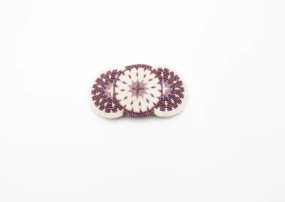 A beautifully crafted beaded hair clip featuring intricate designs in shades of purple and white, set against a plain backdrop.